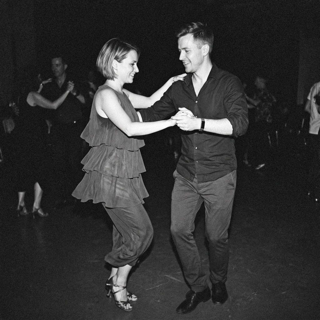 Adult dancers smiling and practising together in a relaxed ballroom dance class