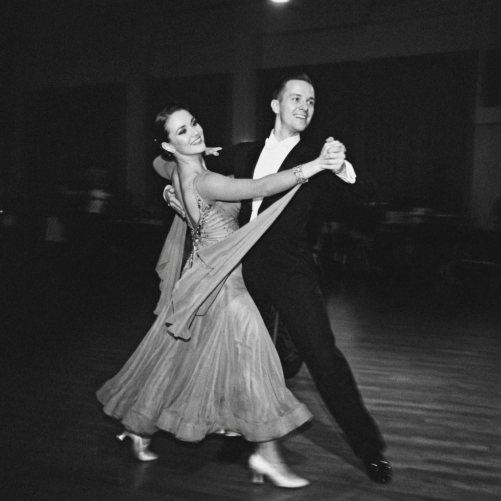 Smiling ballroom dancing couple in dynamic black and white reportage photography